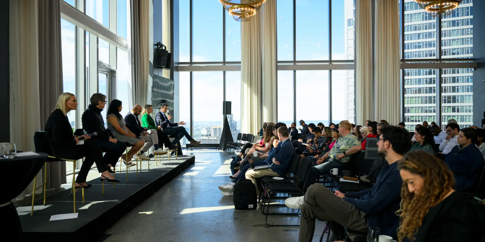 The room during a conversation: the panel along the windows and the audience filling the floor.