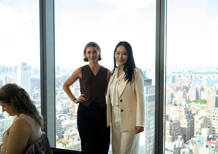 Two attendees by the window, with the city below.